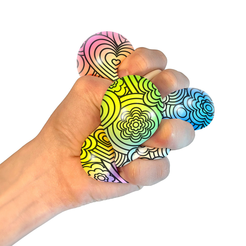 A hand squeezing a NeeDoh Press-Doh C9. The colorful doh is visible through the white and black designs of the exterior.